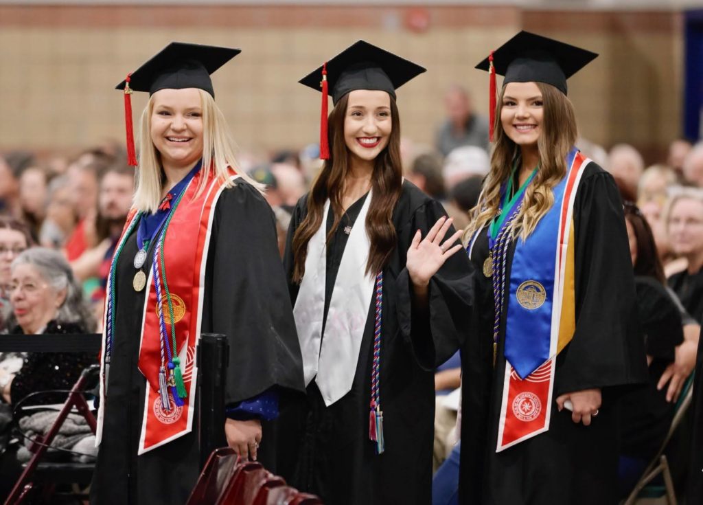 3 girls wearing cap and gown at graduation